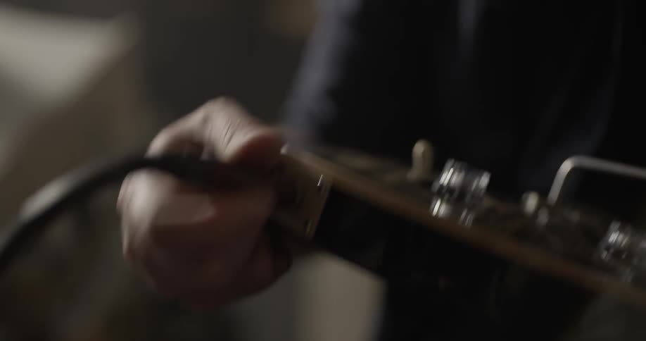 Close up of a person plugging in a guitar