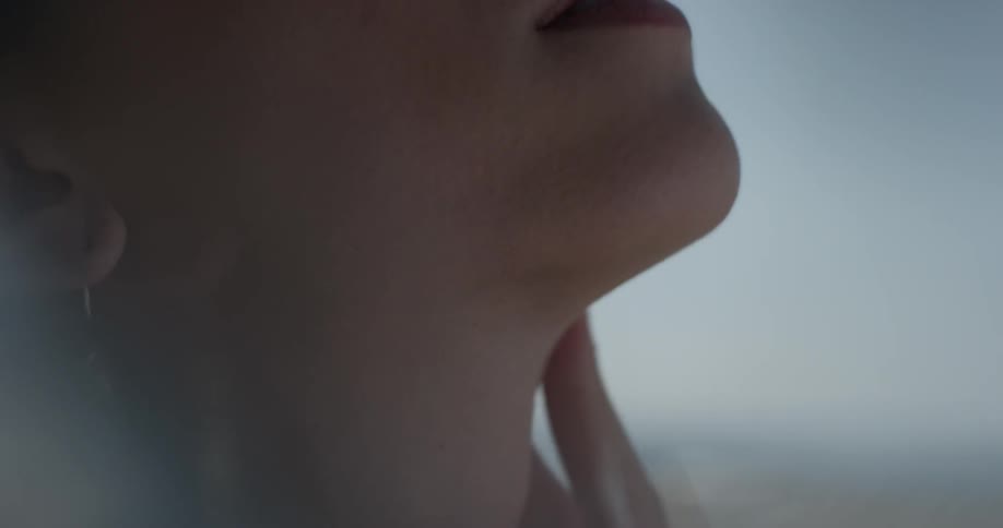 Woman looks closely as she strokes her neck