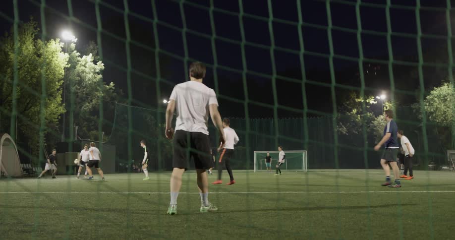 A group of people playing soccer at night