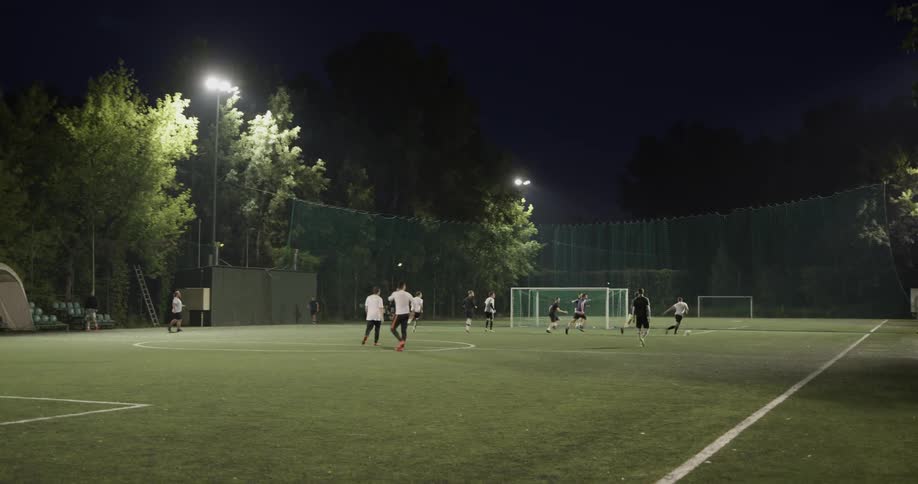 A group of people playing soccer at night