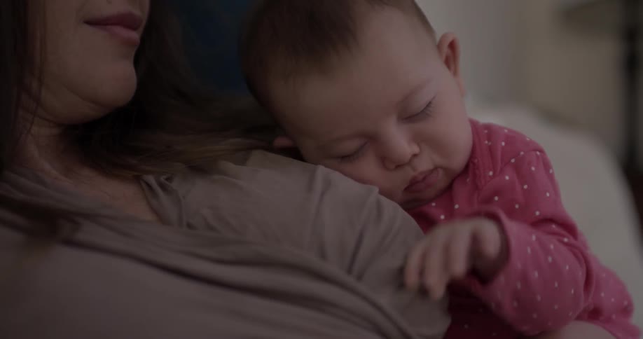 A sleeping baby wiggles on a woman's chest