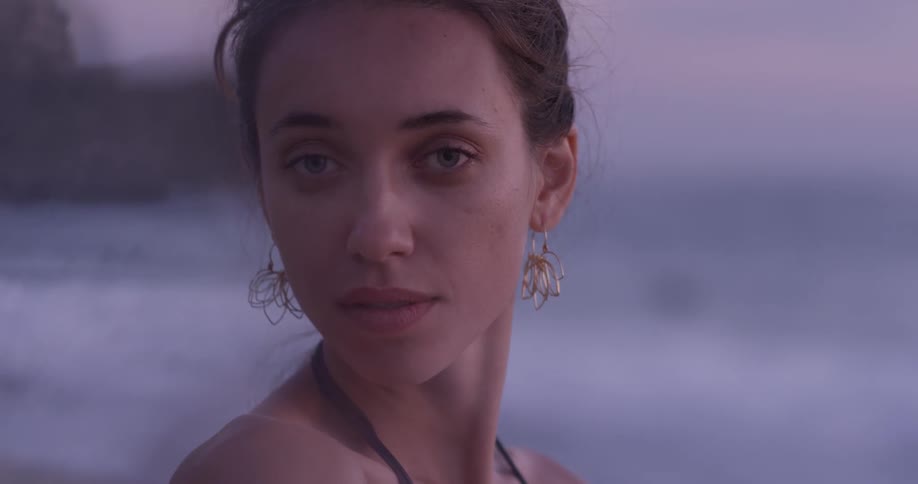 Woman turns from looking at ocean to look over her shoulder