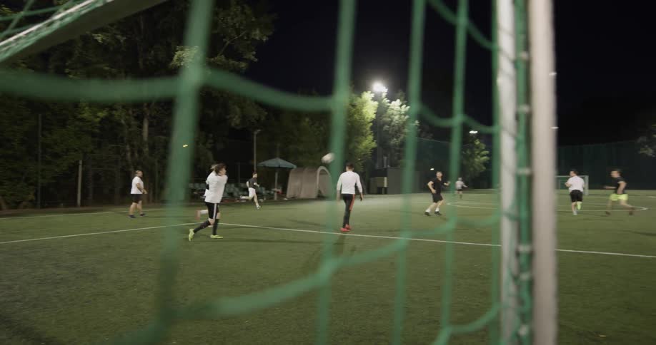 A group of people are playing soccer at night