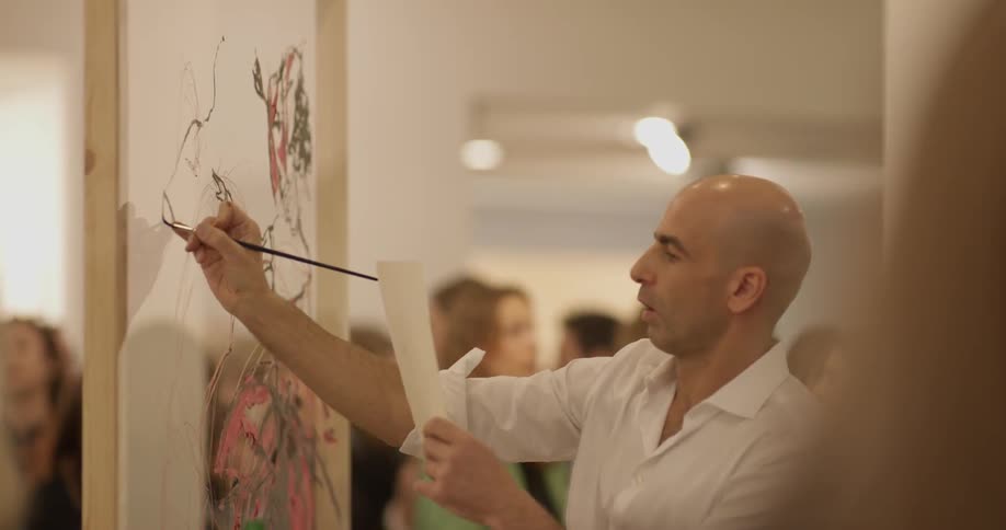 A man is looking at a paper and painting on a large object