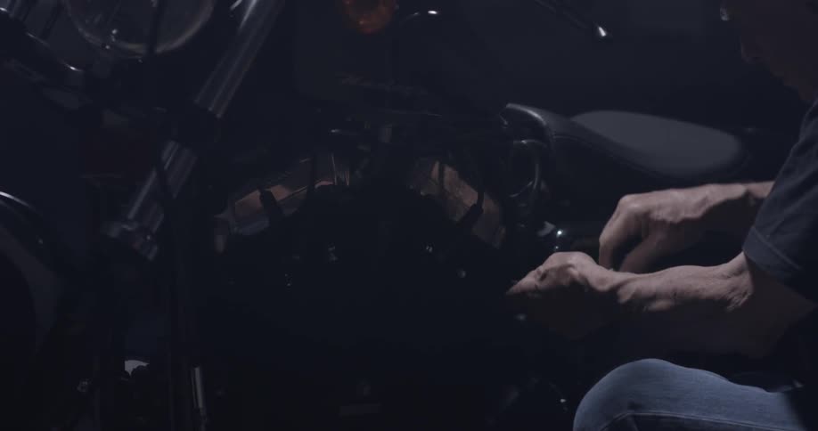A man works on a motorcycle with a ratchet