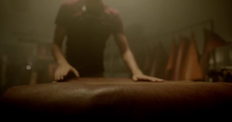 Man lays a piece of leather on a table and smooths it
