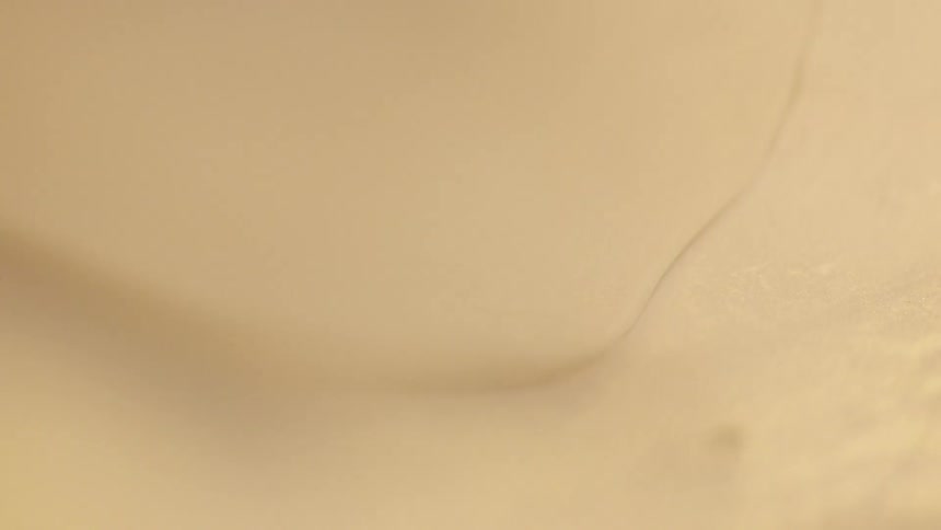 Tan substance drops into  the tan liquid
