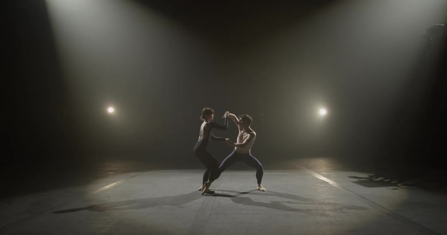 A man runs his hand down a woman's arm and they begin to dance