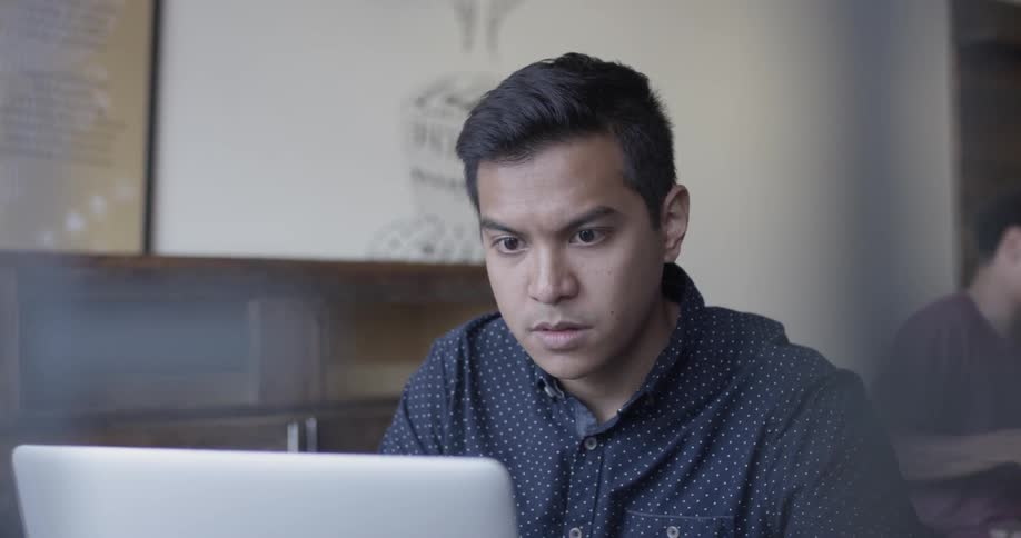 Man works on laptop at cafe table