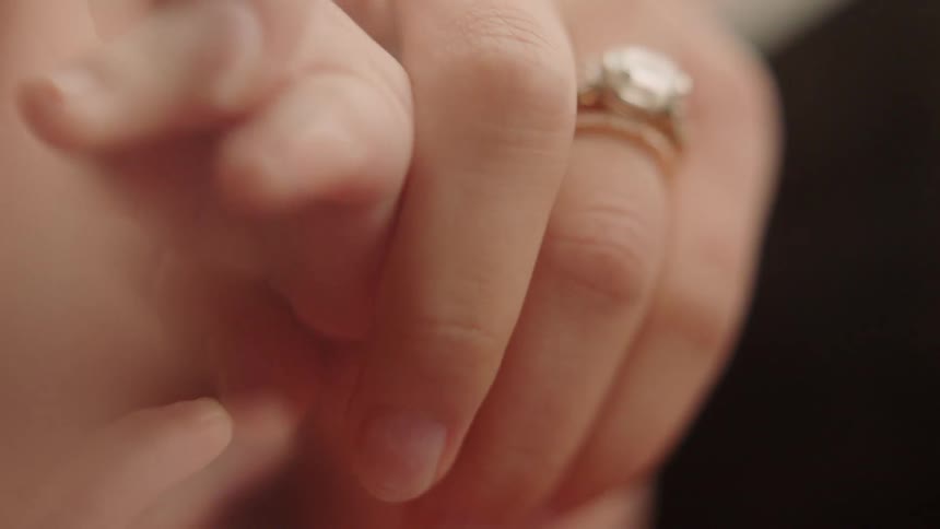 A woman is holding a baby's hand