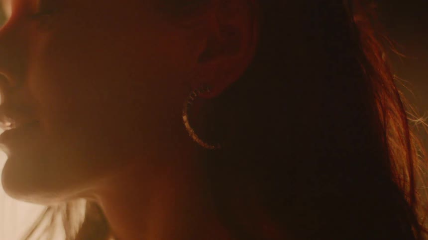 A woman standing in front of a fire slowly opens her eyes and closes her lips