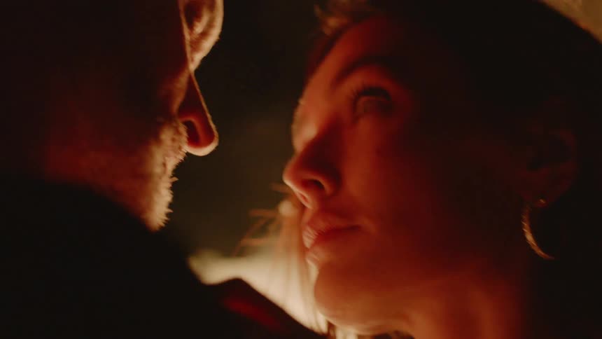 Man and woman stare at each other on a bonfire at night