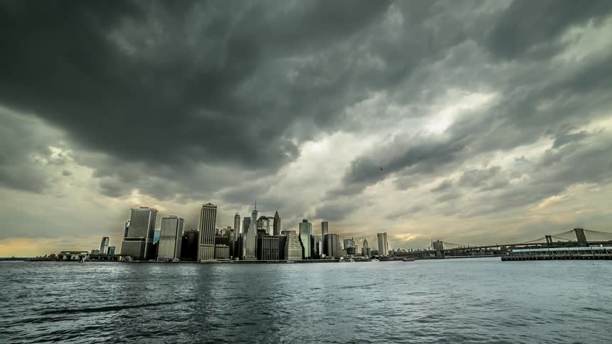 Time lapse of water with boats and rolling clouds near city