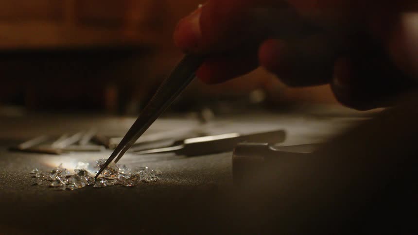 Someone picking up a diamond with tweezers