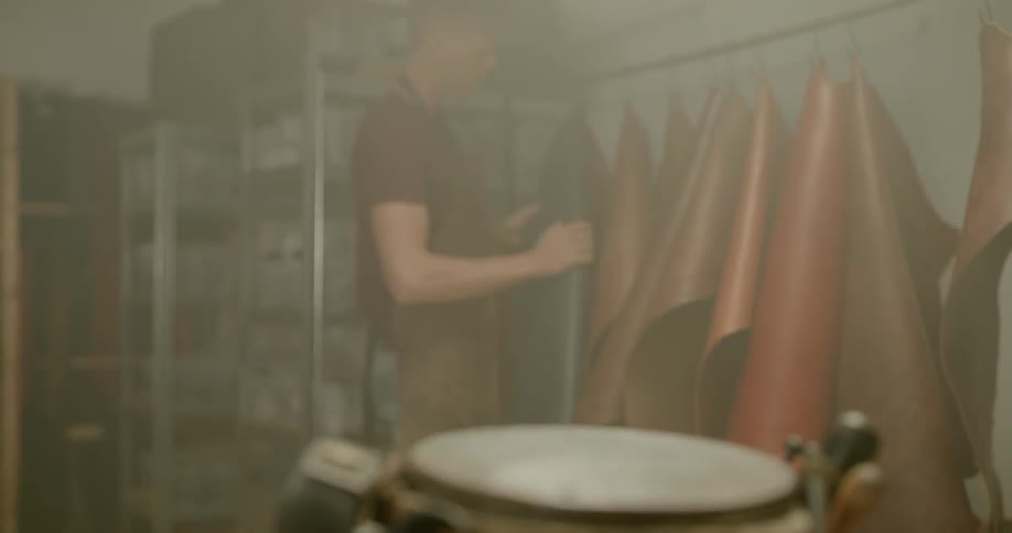 Man lifts a piece of leather off a hook