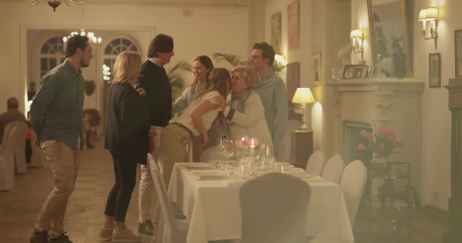 A group of people hugging and talking at a dinner party