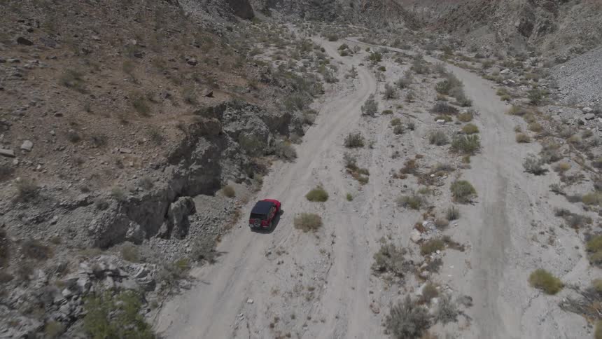 A jeep drives down a dirt road in the desert