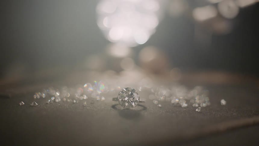 A large diamond ring sitting in a pile of loose diamonds