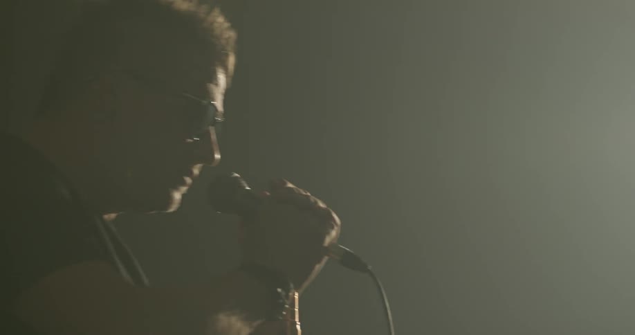 Man holds and sings into microphone