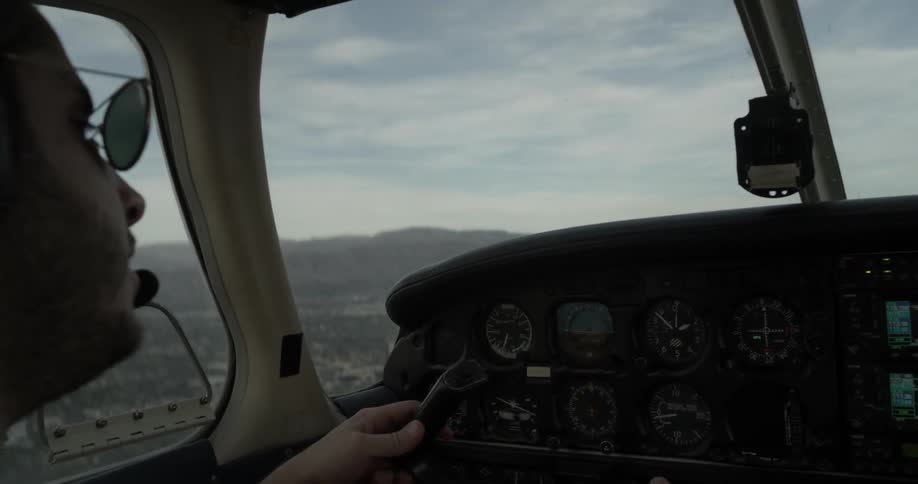 Man flying airplane above city speaks into headset