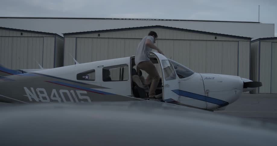 A man opens the door and climbs in an airplane