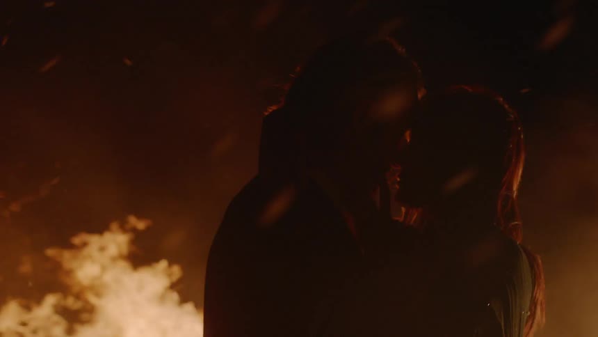 A man and woman kissing in front of a fire