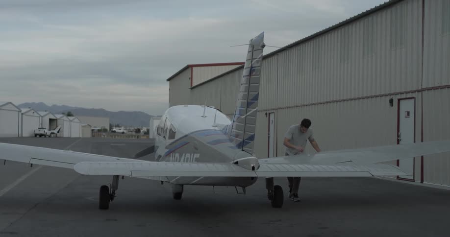 Man walks to a small plane and checks the wing