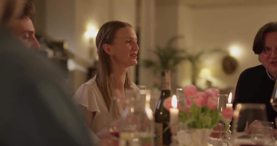 Group of people seated at a table take a sip of wine