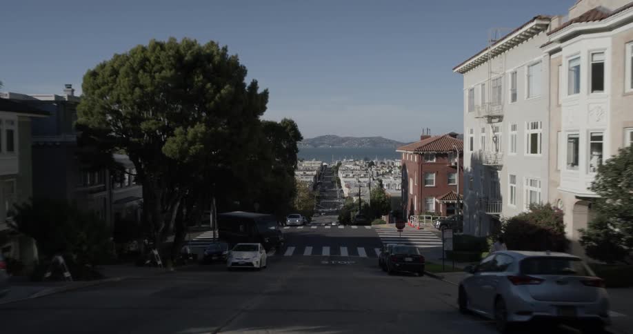 Cars drive down a hill in a city