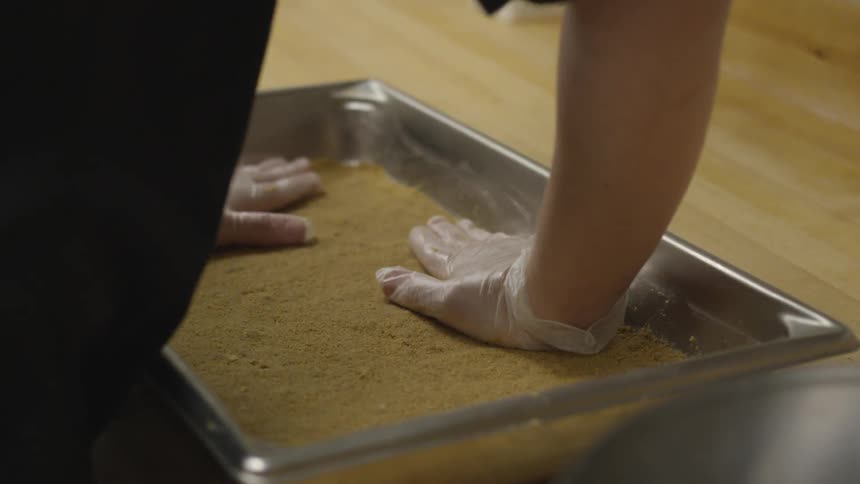 A person is pressing ingredients in a pan