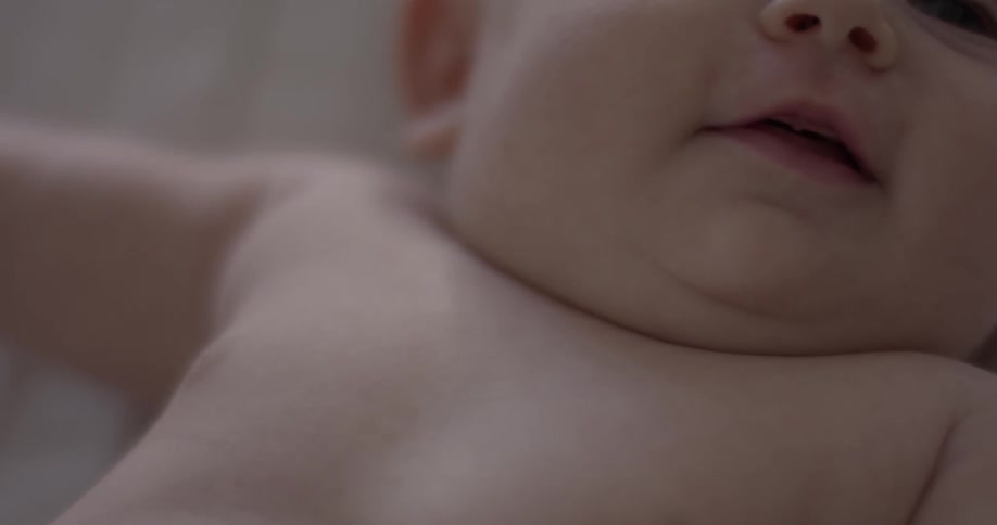 Baby is squirming around on the blankets on top of a bed indoors