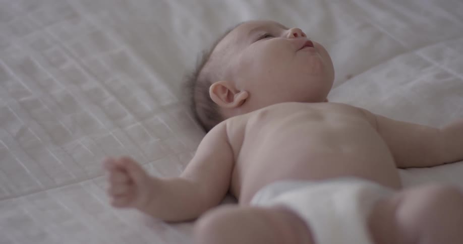 A baby lies on it's back smiling and cooing
