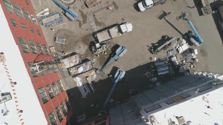Construction vehicles sit at the base of a building