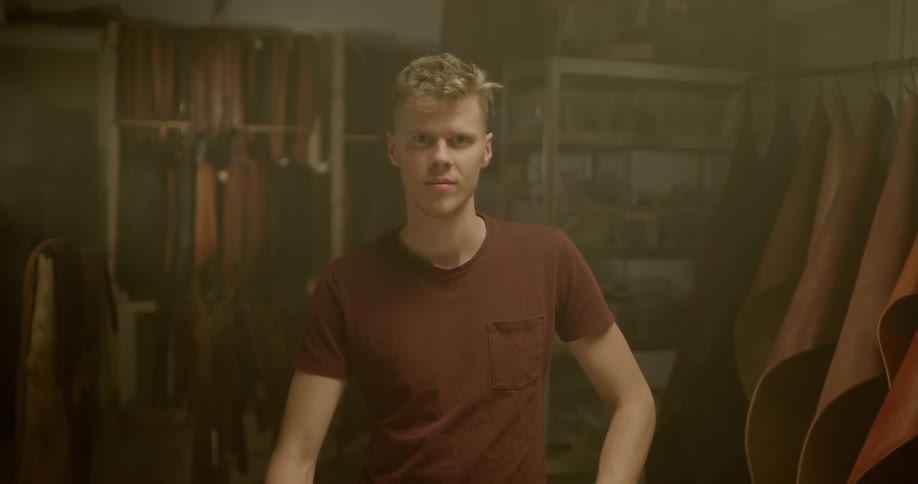 Man stares ahead surrounded by leather scraps