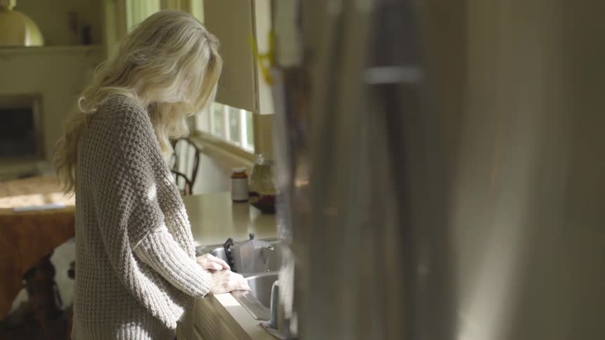 Woman looking in the sink of a kitchen