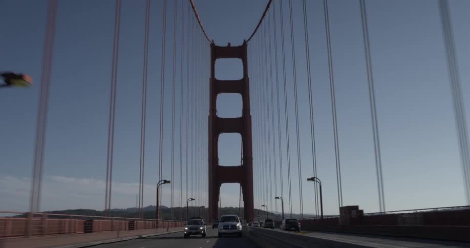 Cars drive on the golden gate bridge near sunset