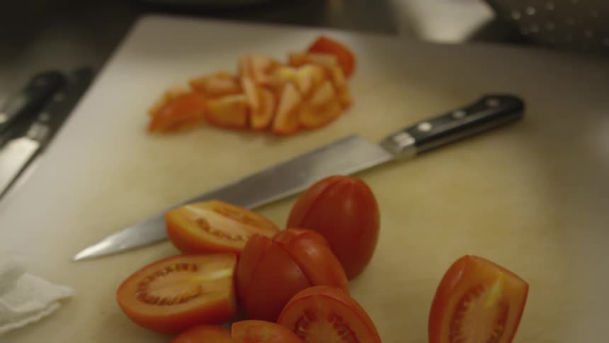 A person is grabbing tomatoes that are cut in half