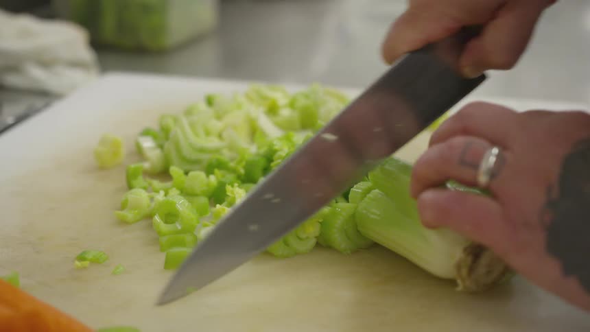 A person is using a knife to cut celery