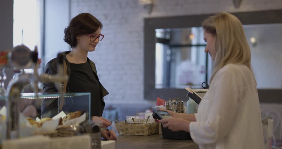 Woman scans her credit card while another woman holds the machine