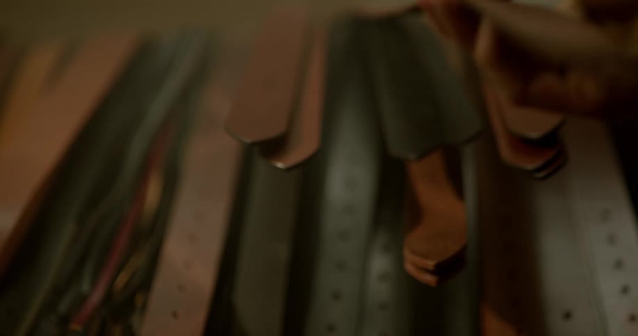 Hand chooses leather shaped into belt from among other belt forms