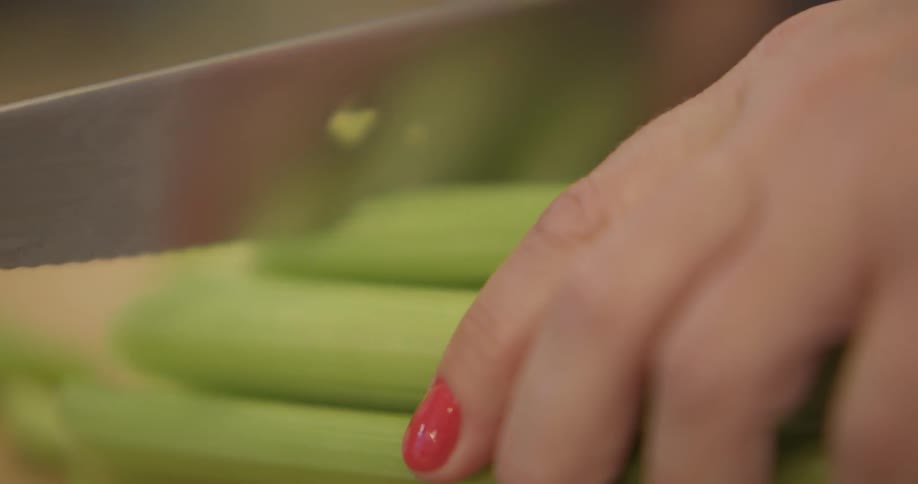 A woman cuts a bundle of celery into chunks