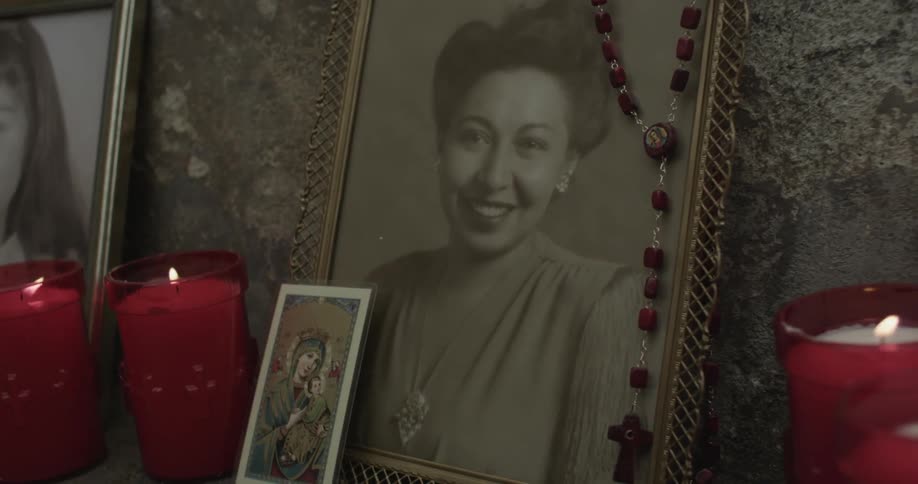 Picture of a woman with candles surrounding it and a rosary