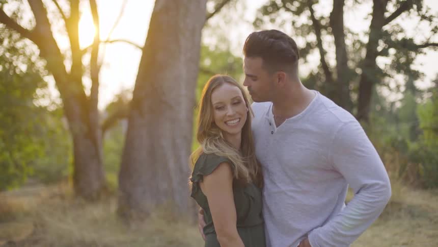 A man kissing a woman in a forest