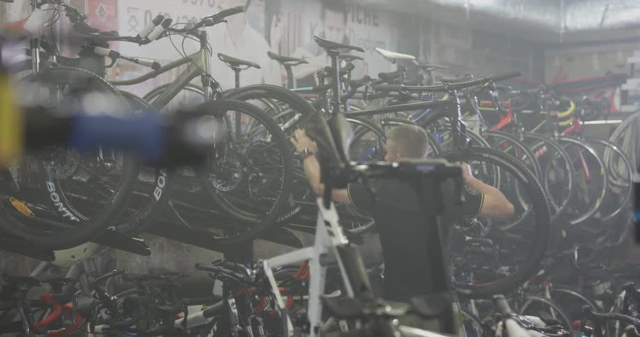 Man places bike on rack in bike shop