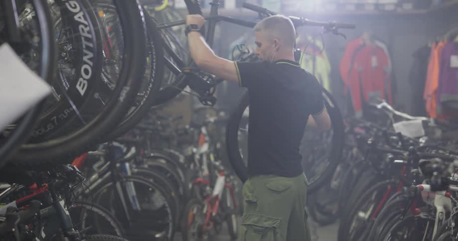 A man is picking up a bike and setting it down