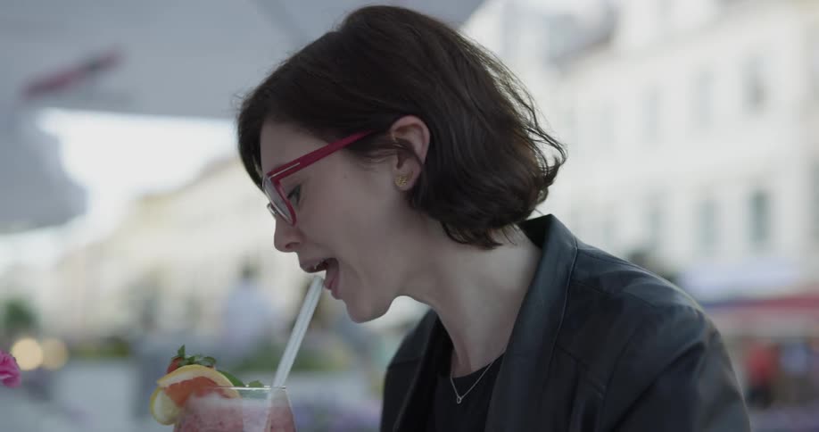 A woman is taking a sip of a drink