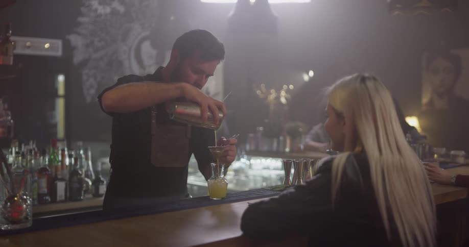 A man is pouring a drink for a woman at a bar