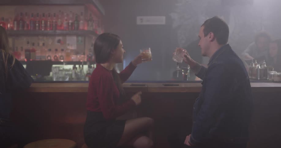 A man and woman cheers at a bar top