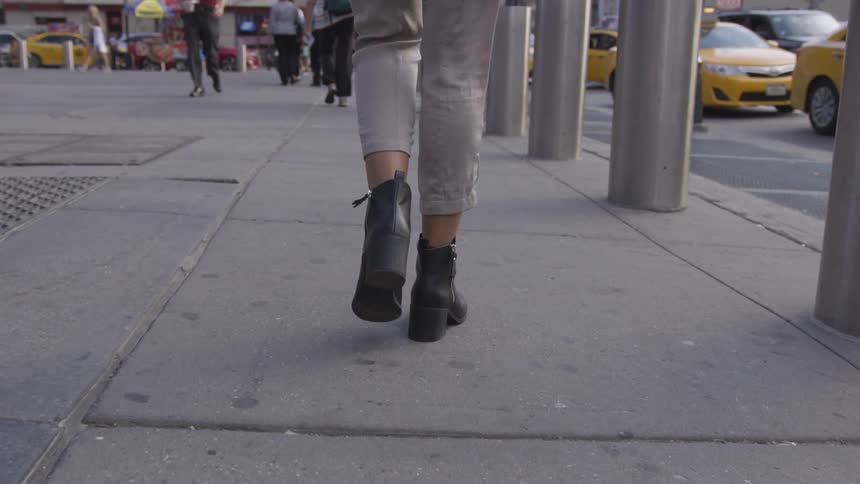 A woman walking down a sidewalk in a city