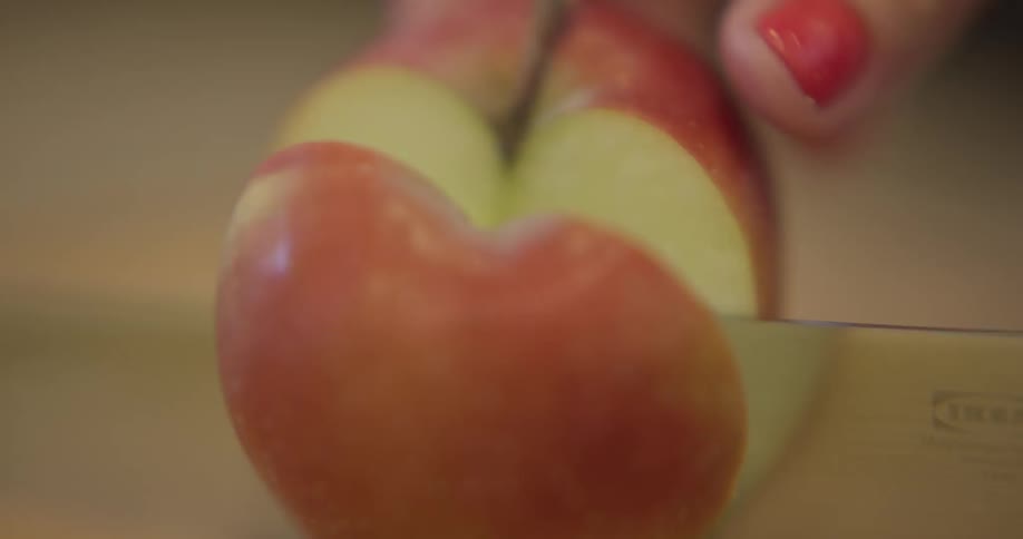 An apple is being cut by a knife